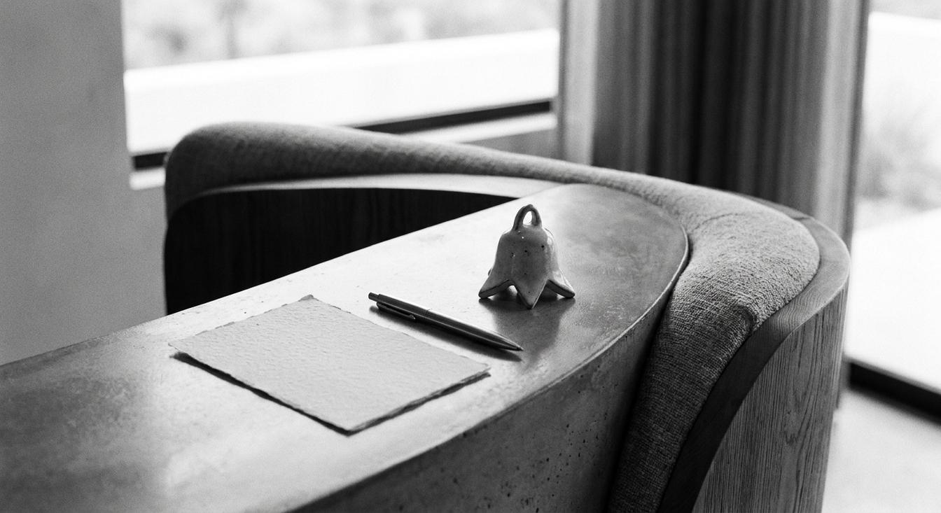 Composición abstracta en escala de grises de una recepción de hotel con una tarjeta de comentarios y un bolígrafo