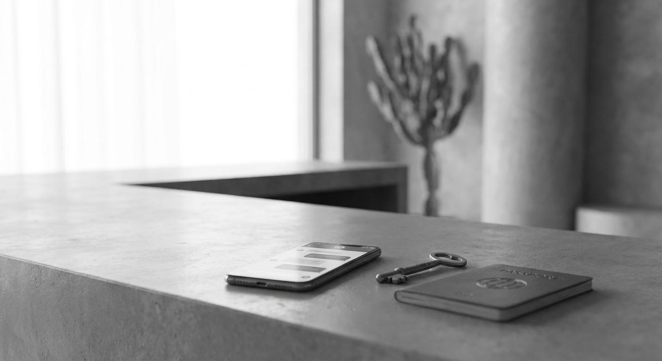 Composición abstracta en escala de grises de una recepción de hotel con un teléfono, una llave y un pasaporte
